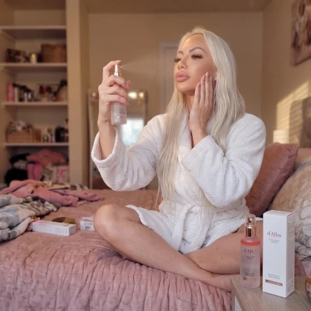 Kobieta rozpylająca odświeżającą mgiełkę d'Alba Vital Spray Serum na twarz dla uzyskania efektu promiennej cery.
